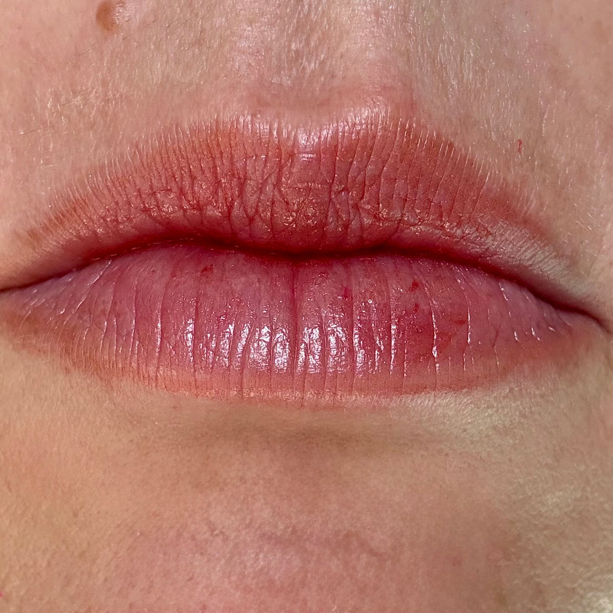 Close-up of lips wearing Wild Rouge tinted lip balm by Noble Skin Co., a bold berry-red tint with a smooth, buildable finish and natural shine
