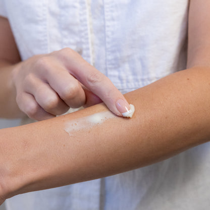 Finger spreading cream on a forearm.