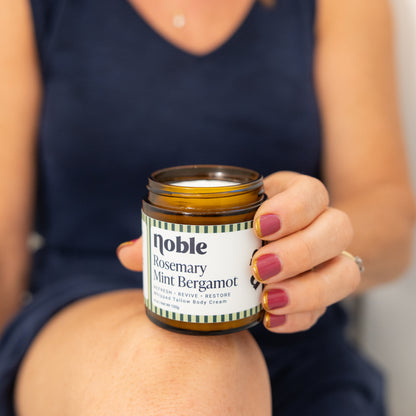 Person holding an open Rosemary Mint Bergamot Body Tallow jar.