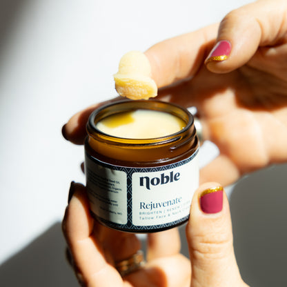 Hands holding an open Rejuvenate Face Cream jar and a scoop of cream.