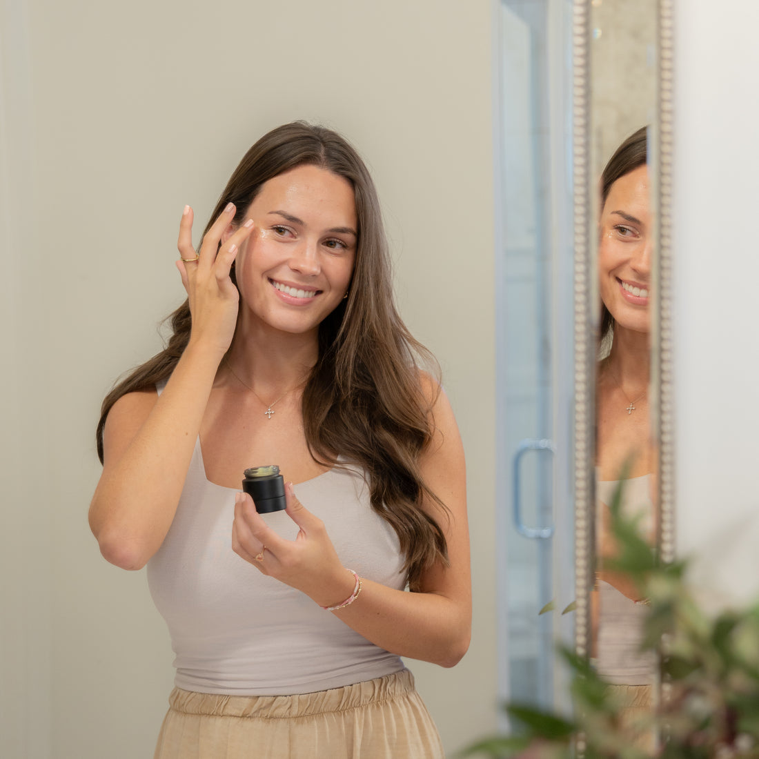 Smiling woman applying balm near her eye.