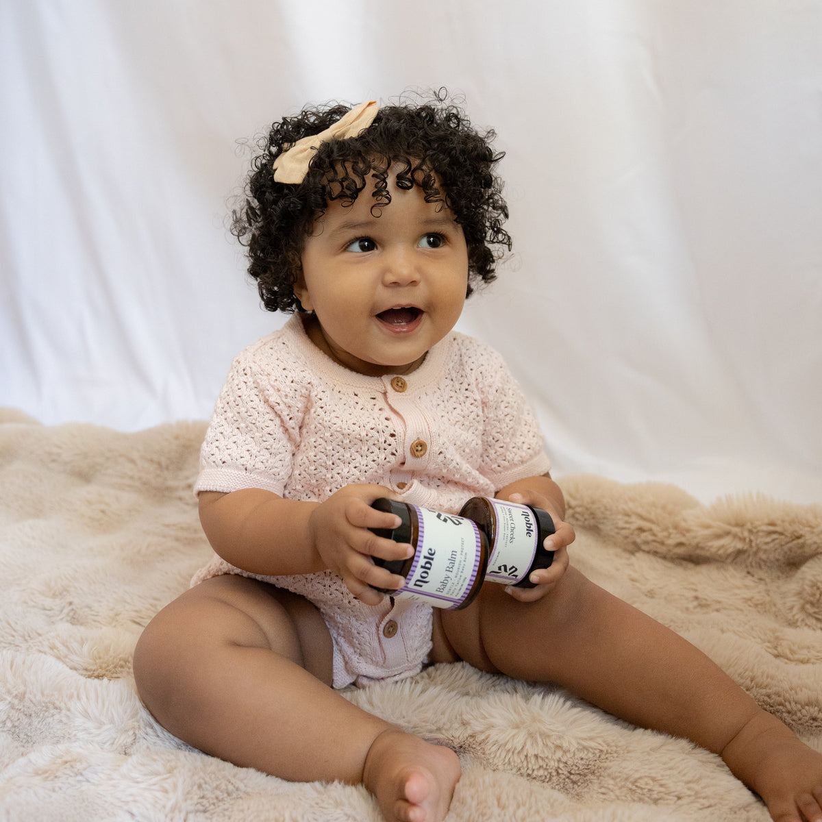 Baby holding a current-label Baby Balm jar.