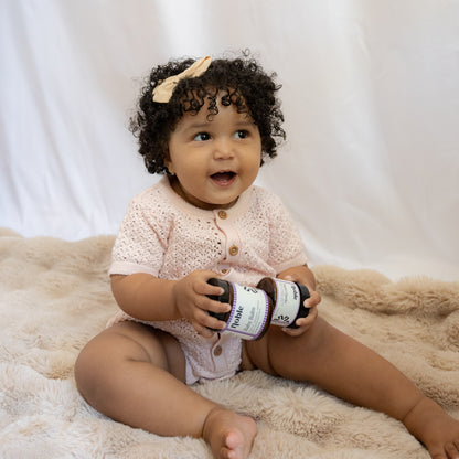 Baby holding a current-label Baby Balm jar.