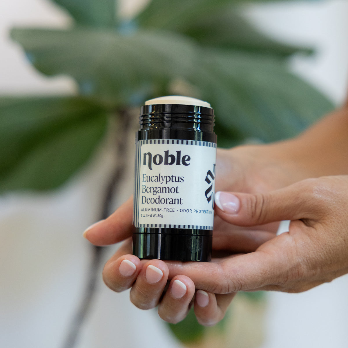 Hand holding an open Eucalyptus Bergamot Deodorant stick.