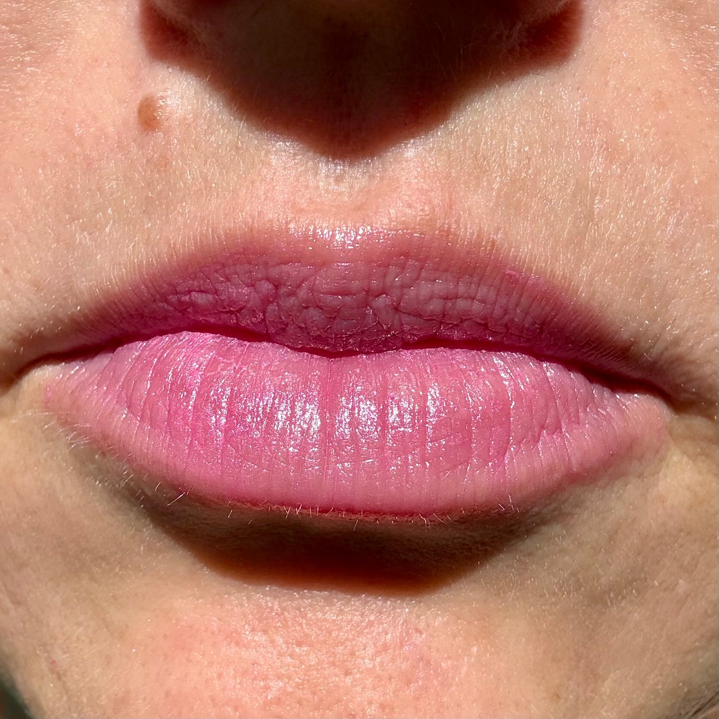 Close-up of lips wearing Electric Orchid tinted lip balm by Noble Skin Co., a vibrant cool-toned orchid pink with a silky, luminous finish