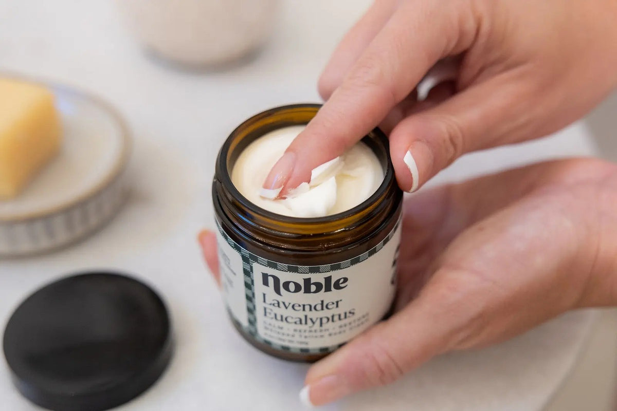 Hands scooping Noble Lavender Eucalyptus Body Tallow from an open jar.