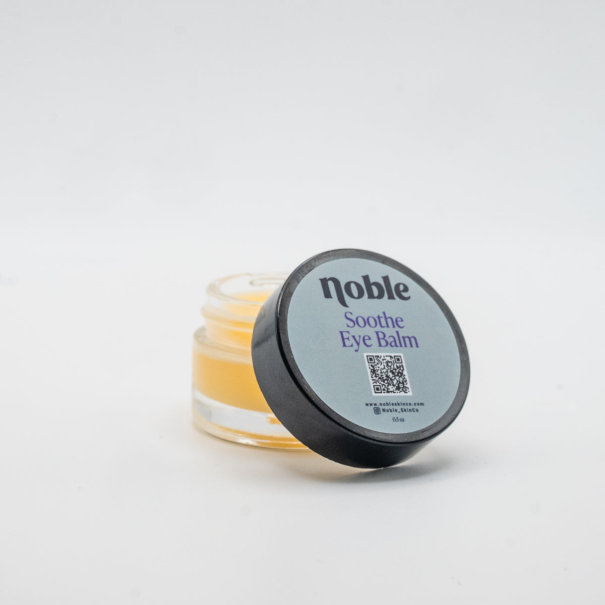 Noble Skin Co. Soothe Eye Balm 0.5 oz open clear glass jar with labeled lid