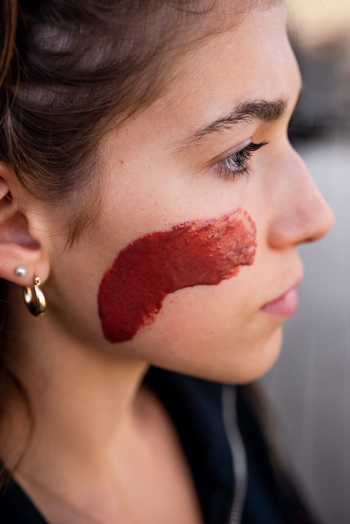 Reddish mask applied to a woman’s cheek.