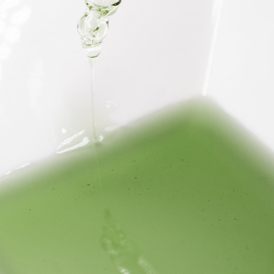 Green Soothe Face Serum beneath a glass dropper.