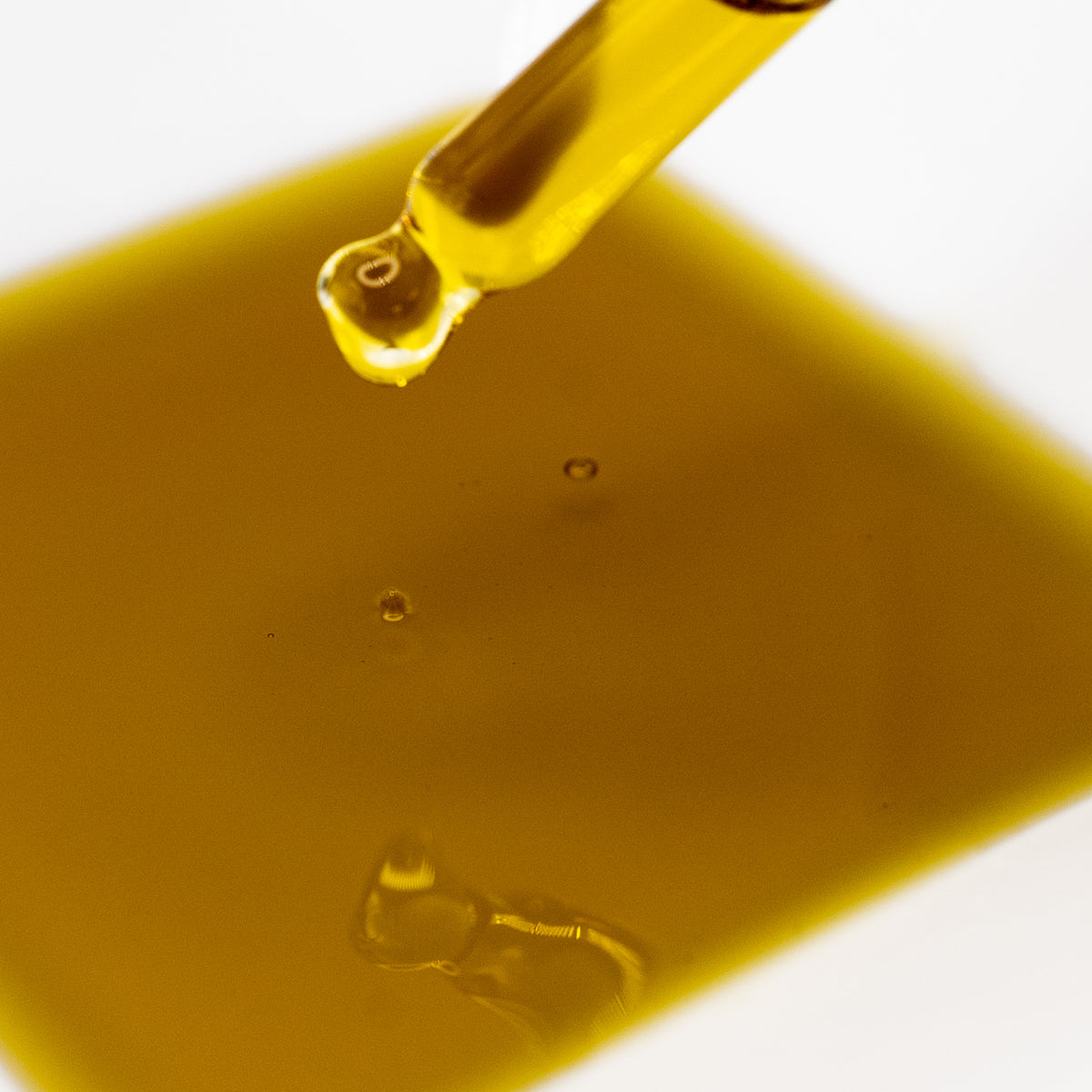 Golden Clarify Face Serum dripping from a glass dropper.