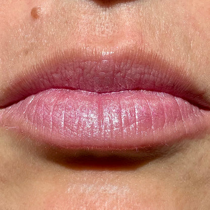 Close-up of lips wearing Pink Fizz tinted lip balm by Noble Skin Co., a light cool pink with a soft shimmer and natural hydration