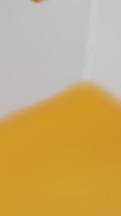 Close-up of golden Rejuvenate Face Serum texture in motion.