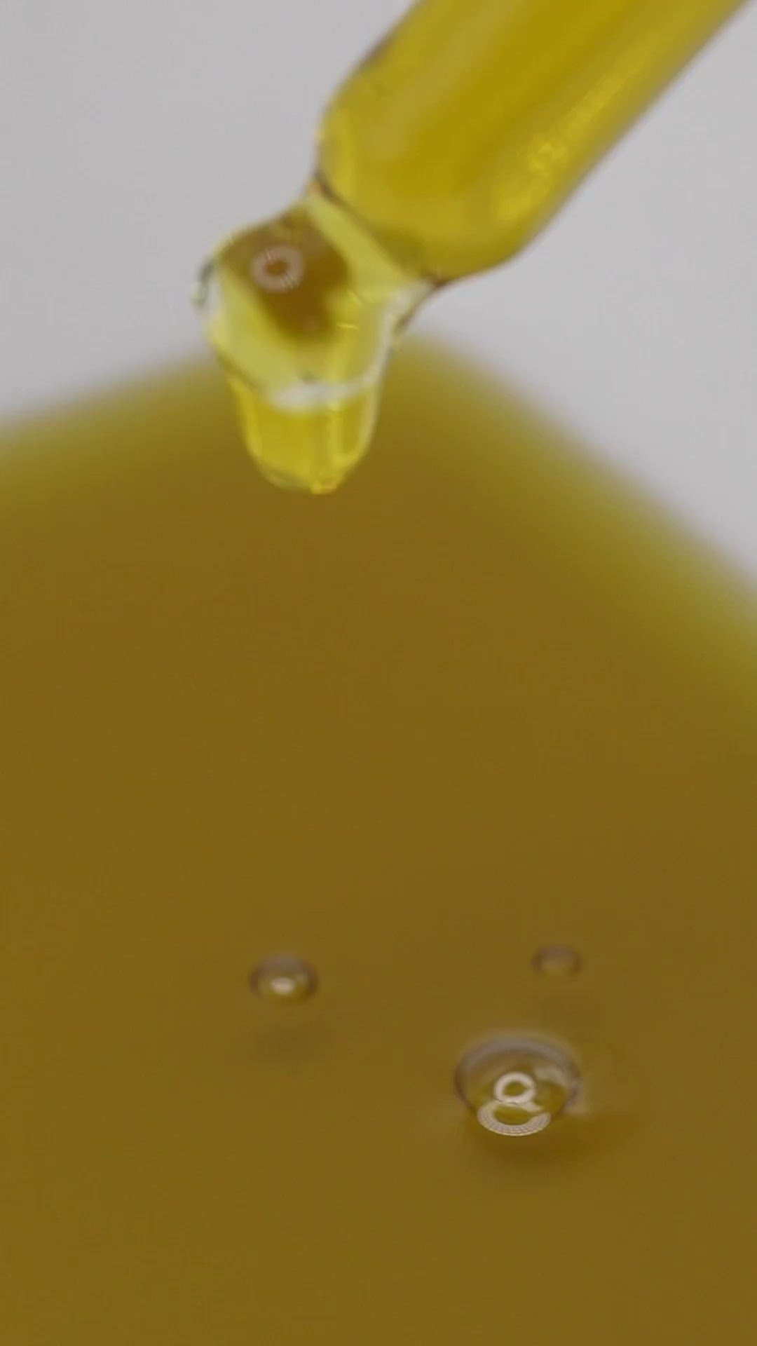 Clarify Face Serum drops falling from a glass dropper.