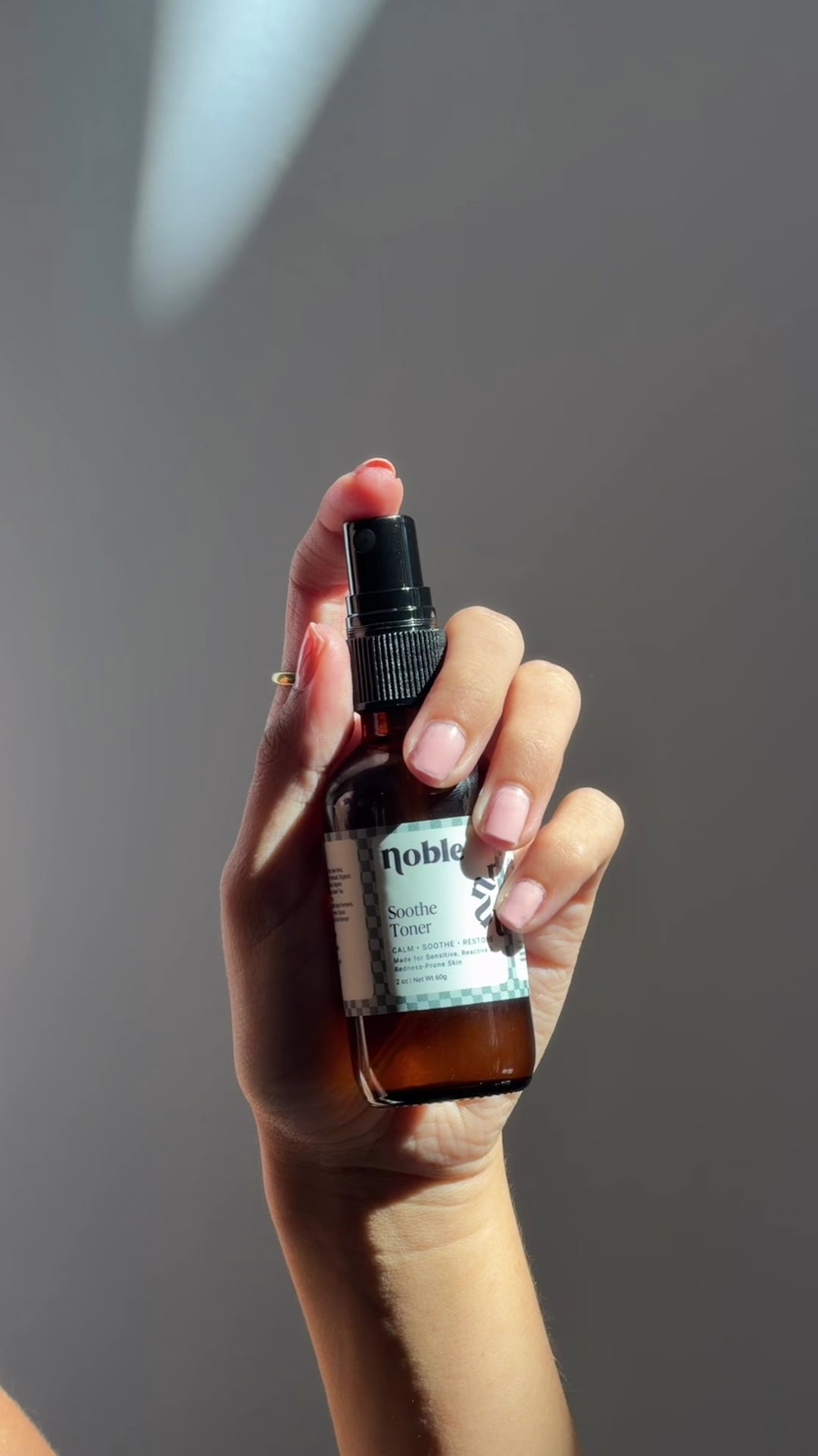 Hand holding a Soothe Toner spray bottle.